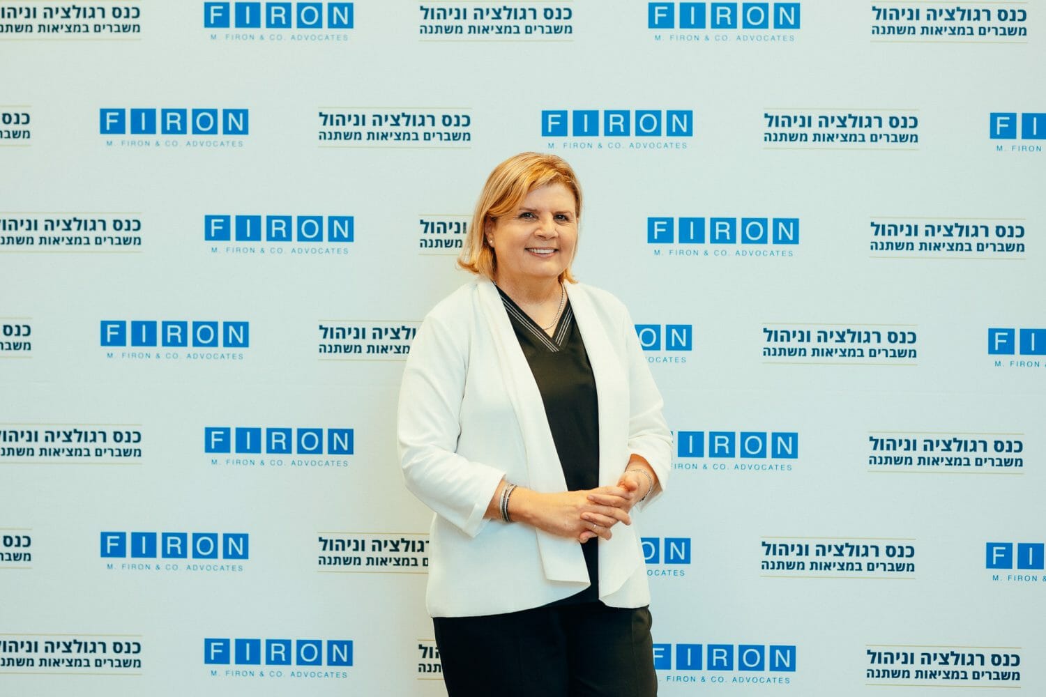 אורנה ברביבאי מצולמת על רקע ממותג של פירון בכנס רגולציה וניהול משברים במציאות משתנה