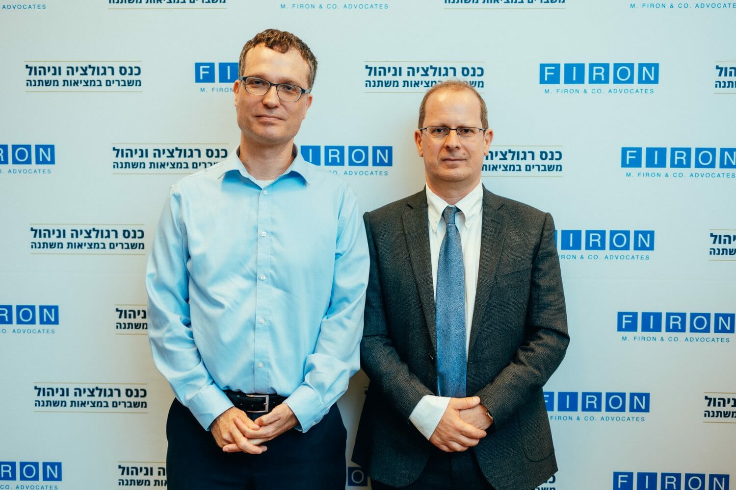 אנשים מצולמים על רקע ממותג של פירון בכנס רגולציה וניהול משברים במציאות משתנה